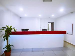 a red counter in a white room with a plant at Smile Hotel Damansara Tropical in Petaling Jaya