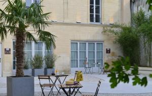 une cour avec des tables et un palmier en face d'un bâtiment dans l'établissement La Maison de Mathilde, à Bayeux