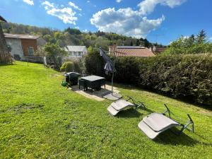 a backyard with a table and chairs in the grass at Maison aux pieds des volcans in Orcines