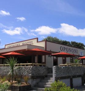 a restaurant with red umbrellas in front of it at Opononi Hotel in Opononi