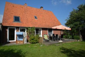 une maison avec une terrasse dotée de chaises et d'un parasol dans l'établissement Ferienhaus Deichstern, à Hoddersdeich