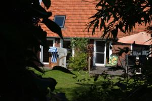 une maison avec une chaise et un parasol dans la cour dans l'établissement Ferienhaus Deichstern, à Hoddersdeich