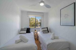 Dos camas en una habitación blanca con ventana. en Pa Le Mer - Sleeps 10 - 4 Mins Walk To Beach - Pet Friendly!, en Culburra Beach