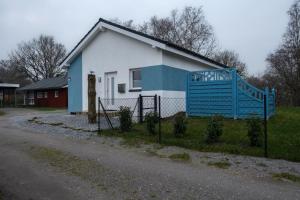 a white and blue house with a fence in front of it at Ferienhaus Möwennest in Sehestedt