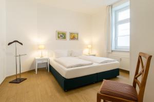 ein Schlafzimmer mit einem Bett und einem Stuhl und einem Fenster in der Unterkunft Villa Aegir Villa Aegir 002 in Heringsdorf
