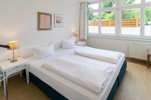 ein weißes Schlafzimmer mit einem großen Bett und einem Fenster in der Unterkunft Villa Aegir Villa Aegir 002 in Heringsdorf