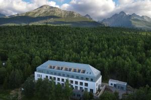 a building in the middle of a forest with mountains at TRITA SK - Lebenski A27 - Infrasauna - Brand new - Parking in Vysoké Tatry