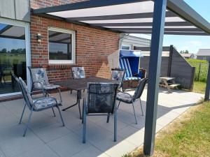 SehestedtにあるFerienhaus Weitblickの日よけの下にテーブルと椅子が置かれたパティオ