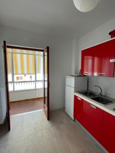 a kitchen with red cabinets and a sink and a window at Mamma Gina in Vieste