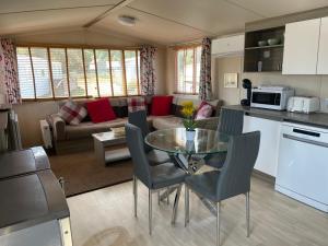 a kitchen and living room with a glass table and chairs at Tingdene caravan park north dene in Lowestoft