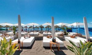 a beach with white lounge chairs and umbrellas at SUITE PLAYA CARIHUELA Apartamentos in Torremolinos
