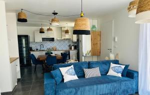a living room with a blue couch and a kitchen at Le Cottage de Felix in Canet d'Aude