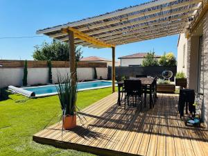 a wooden deck with a table and chairs under a pergola at Le Cottage de Felix in Canet d'Aude