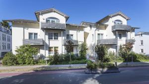 a large white building with balconies on a street at Villa a cappella A6 in Binz