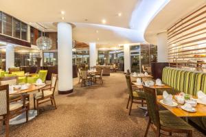 un restaurante con mesas y sillas de madera y un bar en City Lodge Hotel Lynnwood en Pretoria