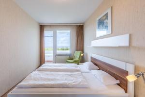 a bedroom with a large bed and a green chair at Haus Atlantic, FeWo 305 in Döse