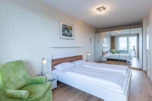 a bedroom with a white bed and a green chair at Haus Atlantic, FeWo 305 in Döse