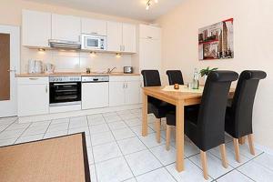 a kitchen with a wooden table and black chairs at Ferienwohnungen Alter Sielweg Wohnung 12 in Bensersiel