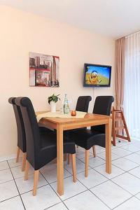 a dining room with a wooden table and black chairs at Ferienwohnungen Alter Sielweg Wohnung 12 in Bensersiel