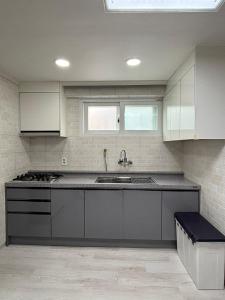 ソウルにあるA spacious two-room accommodation near Gangnam, where dogs are allowedの白いキャビネットとシンクのあるキッチン