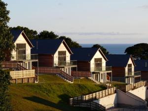 a row of houses on a hill with the ocean in the background at House 30 in Looe