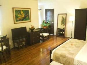 een slaapkamer met een bed, een tafel en een bureau bij Five Princes Hotel in Suva