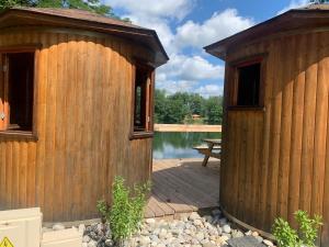 a wooden building with a deck next to a pond at L'Écorce & le Tanin - 2 cabanes cosy pour 4, pêche in Roye +12 photos