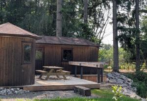 a wooden cabin with a picnic table and a bench at L'Écorce & le Tanin - 2 cabanes cosy pour 4, pêche in Roye