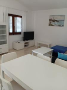 a living room with white furniture and a tv at Apartments Zlata in Lopar