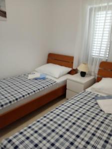 a bedroom with two beds and a table with a lamp at Apartments Zlata in Lopar