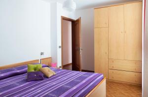 - une chambre avec un lit violet et une armoire en bois dans l'établissement Residence Bonetti, à Rabbi