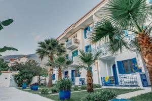 a white building with blue doors and palm trees at Monta Verde Hotel & Villas in Oludeniz