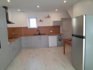 a kitchen with white cabinets and a stainless steel refrigerator at Gîte de l'Aubrigoux - Maison in Saint-Jean-dʼAubrigoux