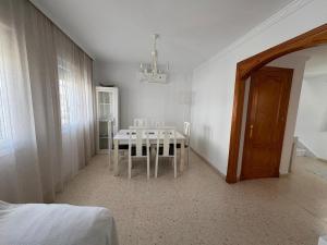 Un comedor blanco con una mesa y sillas. en Casa Rubio, en Chiclana de la Frontera