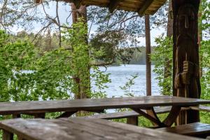 a wooden picnic table with a view of a lake at Poilsio kompleksas Tolieja Vieta renginiams bei poilsiui ant ežero kranto in Kulionys