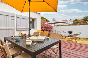 a wooden table with an umbrella on a deck at 700 m de la plage, jardin, maison pour 7 in LʼÉpine
