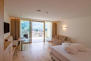 a bedroom with a bed and a living room with a view at Hotel Nocturnes in Naturno