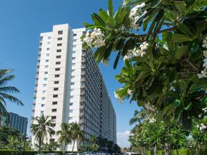 a tall white building with palm trees in front of it at Jomtien Beach Condominium S1 by Olga in Jomtien Beach