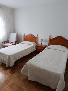 Un dormitorio con dos camas y una silla. en Casa Montse-Izquierda, en Colombres