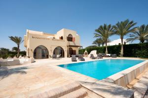 a villa with a swimming pool and palm trees at VESTA - El Gouna Residence in Hurghada +95 photos