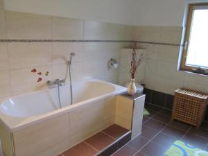 ein Badezimmer mit einer Badewanne und einer Vase aus Blumen in der Unterkunft Large cozy apartment Grubweg 130 qm in Sankt Martin am Tennengebirge