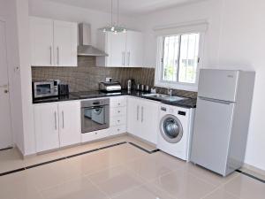 a kitchen with white cabinets and a washer and dryer at Coral Bay Apartment - Prime Tourist Location in Coral Bay