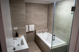 a bathroom with a shower and a tub and a sink at Pelican Shore Oceanfront Villa 6 in Kalbarri +6 photos