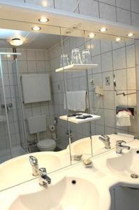 a bathroom with two sinks and a large mirror at Hotel-Restaurant zum Roeddenberg in Osterode