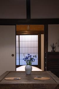 Eine Blumenvase auf einem Tisch vor einem Spiegel in der Unterkunft ëighten Private Guesthouse Yoga Retreat 一棟貸切古民家宿エイテン in Hokuto + 36 Fotos