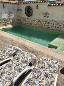 a swimming pool with two beds next to a building at Casa Rural Abuelo Pedro in Cuerva