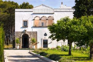 Una casa blanca con un árbol delante. en Critabianca - Masseria in Salento en Cutrofiano