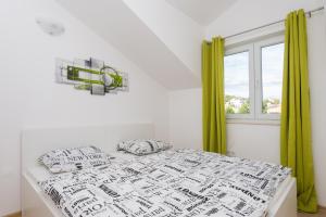 a white bedroom with a bed with green curtains at M.G Apartments in Brodarica