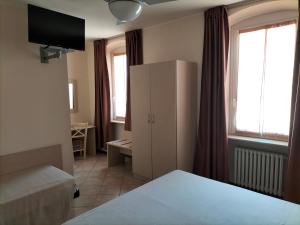 sypialnia z łóżkiem i szafką oraz 2 oknami w obiekcie Albergo Grifone 1891 w mieście Peschiera del Garda