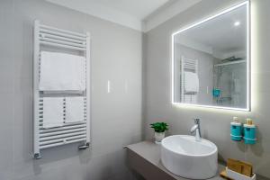 biała łazienka z umywalką i lustrem w obiekcie Novotel Parma Centro w mieście Parma